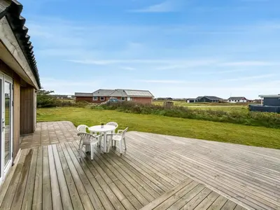 a wooden deck with a table and chairs on it at Holiday Home Olesia - 250m from the sea by Interhome in Harboør