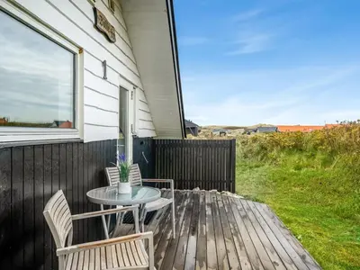 a patio with a table and chairs on a deck at Holiday Home Olesia - 250m from the sea by Interhome in Harboør