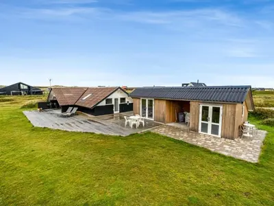a house with a large deck in a field at Holiday Home Olesia - 250m from the sea by Interhome in Harboør