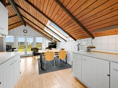 a kitchen with white cabinets and a table with chairs at Holiday Home Olesia - 250m from the sea by Interhome in Harboør