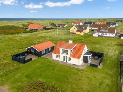 a house with an orange roof on a green field at Holiday Home Dietlinde - 100m from the sea by Interhome in Harboør