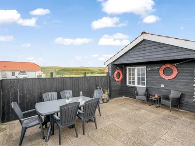 a patio with a table and chairs and a shed at Holiday Home Dietlinde - 100m from the sea by Interhome in Harboør