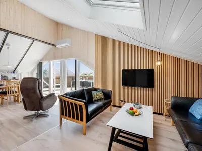 a living room with a couch and a table at Holiday Home Arla - 200m from the sea by Interhome in Harboør