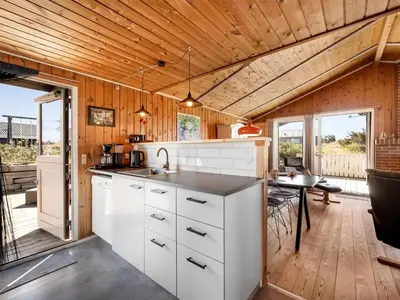 a kitchen with white cabinets and a dining table at Holiday Home Brigit - 200m from the sea by Interhome in Harboør