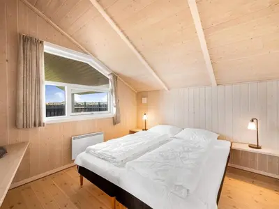 a large bed in a room with a window at Holiday Home Eemil - 700m from the sea by Interhome in Harboør