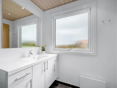 a white bathroom with two sinks and a window at Holiday Home Tanea - 700m to the fjord by Interhome in Lemvig