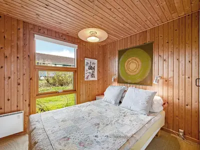a bedroom with a bed in a wooden wall at Holiday Home Tanea - 700m to the fjord by Interhome in Lemvig