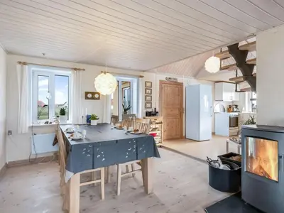 a kitchen and living room with a table and a fireplace at Holiday Home Ali - 75m from the sea by Interhome in Harboør