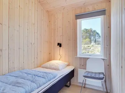 a bed in a room with a window and a chair at Holiday Home Gyrial - 950m from the sea by Interhome in Torsted