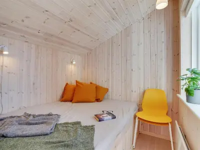 a small room with a bed and a yellow chair at Holiday Home Gyrial - 950m from the sea by Interhome in Torsted