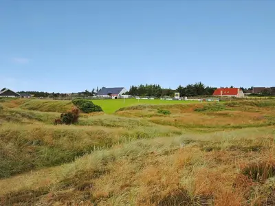 a field of grass with houses in the background at Holiday Home Melanie - 950m from the sea by Interhome in Torsted