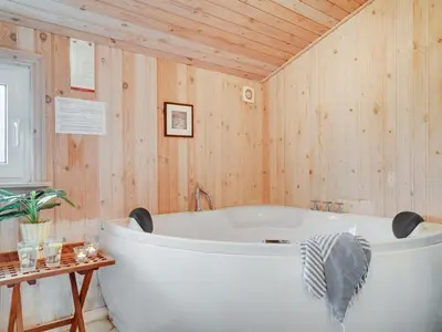 a bath tub in a bathroom with wooden walls at Holiday Home Melanie - 950m from the sea by Interhome in Torsted