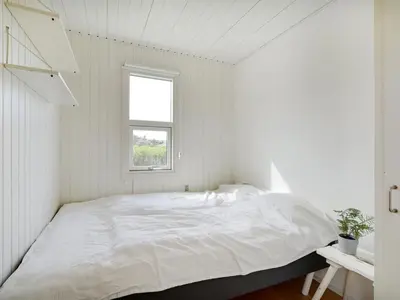 a white bedroom with a large bed with a window at Holiday Home Vilja - 150m from the sea by Interhome in Torsted