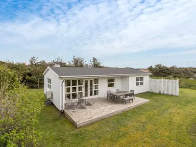 a small white cottage with a deck and a table at Holiday Home Vilja - 150m from the sea by Interhome in Torsted