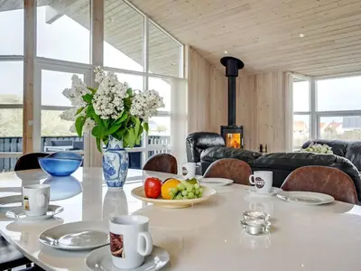 a dining room with a table with a vase of flowers at Holiday Home Frido - 400m from the sea by Interhome in Torsted