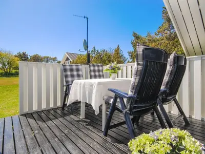 two chairs and a table on a deck at Holiday Home Sakulf - 600m from the sea by Interhome in Torsted