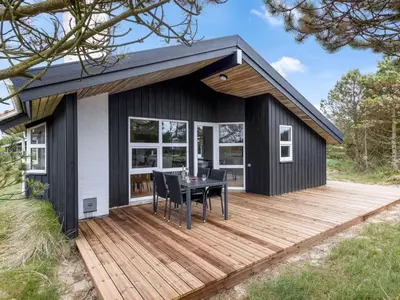 a black and white house with a wooden deck at Holiday Home Antto - 900m from the sea by Interhome in Torsted