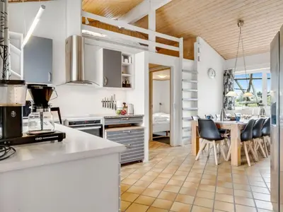 a kitchen with white cabinets and a table with chairs at Holiday Home Palli - 600m from the sea by Interhome in Torsted