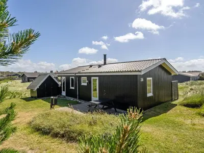 a small black house in the middle of a field at Holiday Home Usko - 250m from the sea by Interhome in Torsted