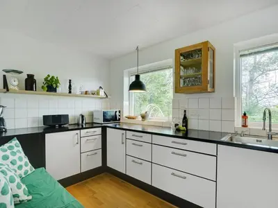 a kitchen with white cabinets and a black counter top at Holiday Home Flor - 900m from the sea by Interhome in Torsted