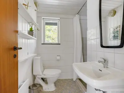 a white bathroom with a toilet and a sink at Holiday Home Fidelia - 800m from the sea by Interhome in Torsted