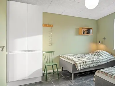 a bedroom with a bed and a chair at Holiday Home Pontus - 400m from the sea by Interhome in Torsted