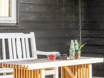 a wooden table with two chairs and bottles on it at Holiday Home Horsten - 350m from the sea by Interhome in Torsted