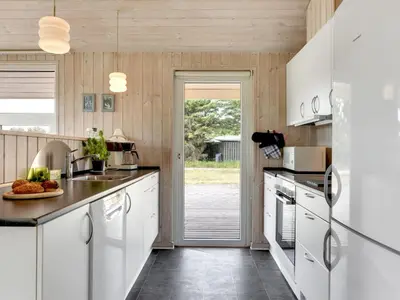 a kitchen with white cabinets and a refrigerator at Holiday Home Annemia - 200m from the sea by Interhome in Torsted