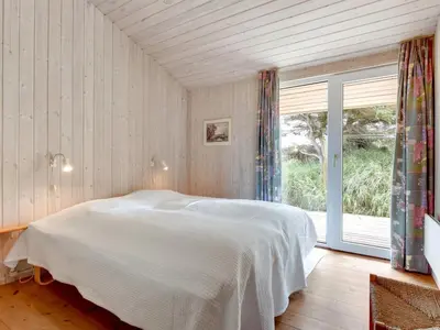 a bedroom with a white bed and a large window at Holiday Home Annemia - 200m from the sea by Interhome in Torsted