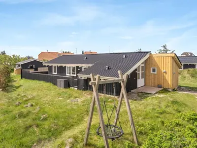 a house with a wooden structure in the grass at Holiday Home Gerlis - 75m from the sea by Interhome in Torsted