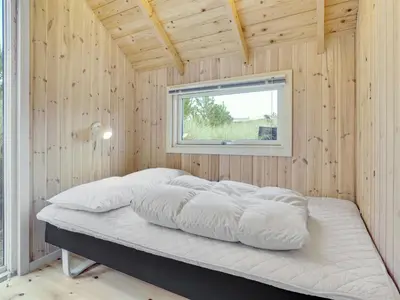 a bed in a wooden room with a window at Holiday Home Tameran - 700m from the sea by Interhome in Torsted
