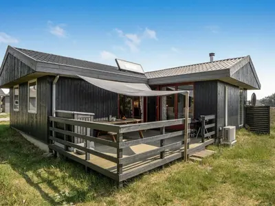 a black tiny house with a porch and a deck at Holiday Home Chumani - 900m from the sea by Interhome in Torsted