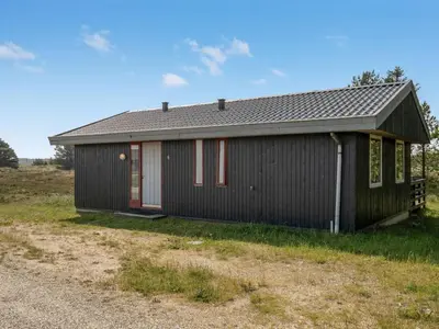 a black house with red doors in a field at Holiday Home Chumani - 900m from the sea by Interhome in Torsted