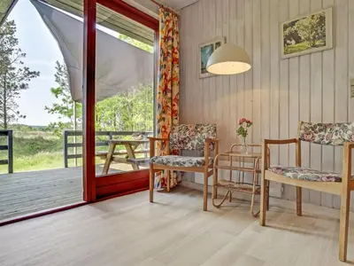 a room with two chairs and a porch with a table at Holiday Home Chumani - 900m from the sea by Interhome in Torsted