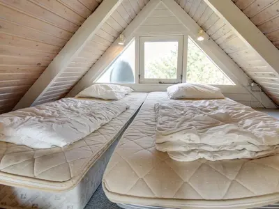 two beds in a attic bedroom with a window at Holiday Home Algonda - 500m from the sea by Interhome in Torsted