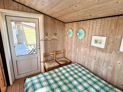 a bedroom with a bed and a door and a chair at Holiday Home Bera - 250m from the sea by Interhome in Torsted