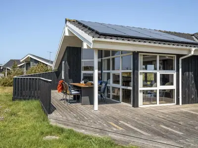 a house with a wooden deck with a table at Holiday Home Emppu - 400m from the sea by Interhome in Torsted