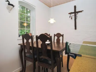 a dining room table with chairs and a cross on the wall at Holiday Home Ludovic - 7km from the sea by Interhome in Thisted