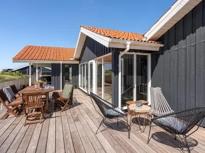 a wooden deck with chairs and a table on it at Holiday Home Milena - 600m from the sea by Interhome in Torsted