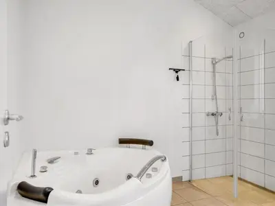 a white bathroom with a tub and a shower at Holiday Home Raakel - 950m from the sea by Interhome in Torsted