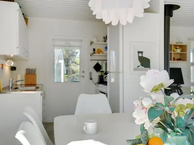 a kitchen and dining room with a white table and flowers at Holiday Home Majgull - 150m from the sea by Interhome in Torsted