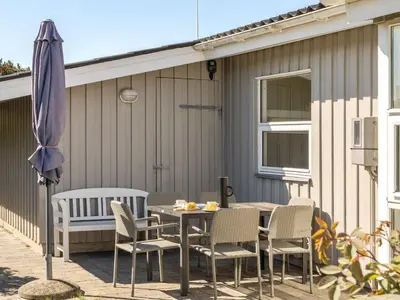 a patio with a table and chairs and an umbrella at Holiday Home Majgull - 150m from the sea by Interhome in Torsted