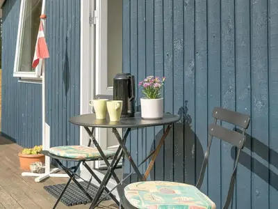 a table with two chairs and flowers on a patio at Holiday Home Hughlek - 900m from the sea by Interhome in Torsted