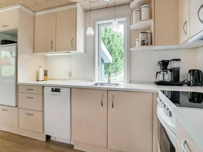 a kitchen with white cabinets and a window at Holiday Home Hughlek - 900m from the sea by Interhome in Torsted