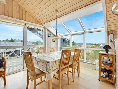a dining room with a table and chairs and windows at Holiday Home Viktorija - 800m from the sea by Interhome in Torsted