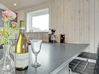 a bottle of wine and a wine glass on a counter at Holiday Home Mavis - 800m from the sea by Interhome in Torsted