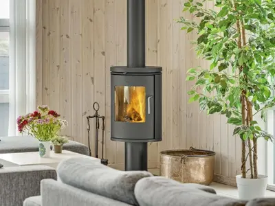 a wood stove in a living room with two couches at Holiday Home Mavis - 800m from the sea by Interhome in Torsted