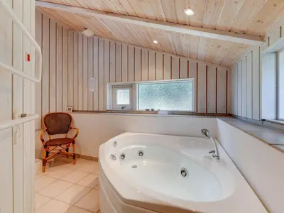 a white bath tub in a bathroom with a chair at Holiday Home Rink - 150m from the sea by Interhome in Torsted