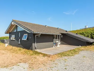 a small house with a wooden deck in front of it at Holiday Home Rink - 150m from the sea by Interhome in Torsted
