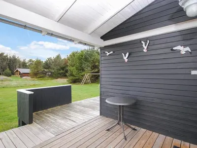 a patio with a stool and a wall with birds on it at Holiday Home Amber - 500m from the sea by Interhome in Torsted